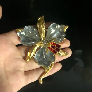 Détail de la broche orchidée vintage avec métal doré et résine effet nuage et cristaux brillants.