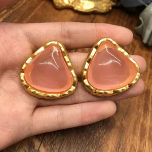 Vintage pink jelly earrings detail, elegant gold geometric design stud earrings close up.