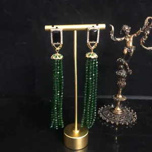 Detailed close-up of long green beaded tassel earrings with black stone and rhinestones.