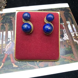 Close-up detail of vintage style gold-plated braided drop earrings with blue stone spheres.
