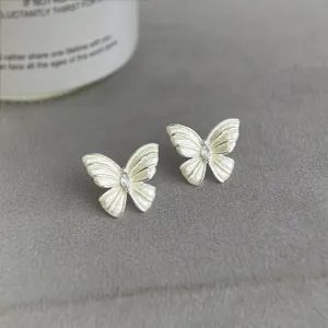 Detailaufnahme von eleganten, weißen Schmetterlings-Ohrringen mit funkelndem Zirkon.