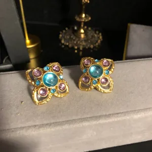 Vintage style clover floral earrings detail, gold-tone metal with blue and purple stones.