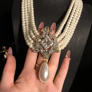 Vintage multi-layer pearl necklace with ornate rhinestone pendant and teardrop pearl detail.