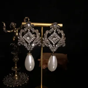 Close-up of vintage baroque palace style drop earrings with rhinestones and faux pearls.