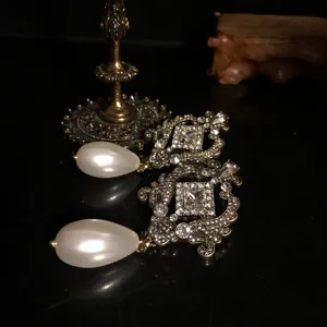 Close-up detail of vintage court style baroque earrings with sparkling rhinestones and large drop pearl.