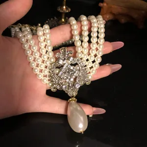 Vintage palace style multi-strand faux pearl necklace with ornate rhinestone pendant