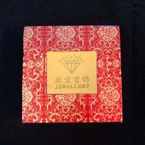 Vue détaillée de la boîte à bijoux rouge avec motif doré pour bagues et colliers.