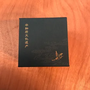 Vue détaillée d'une boîte cadeau à bijoux noire avec motif de grue dorée et texte culturel.