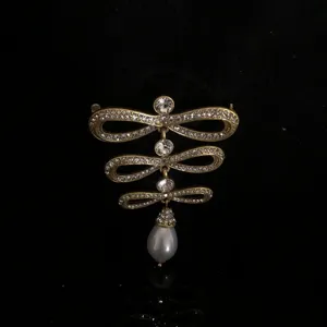 Detail shot of vintage court style rhinestone bow brooch with teardrop pearl pendant.