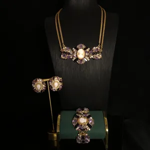 Close-up view of the vintage cameo pendant, purple crystal rhinestones, and gold necklace detail.