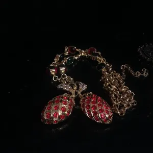 Elegante lange trui ketting met dubbele ananas hanger bezet met rode en groene strass steentjes.