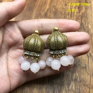 Close-up detail view of vintage aged gold pink crystal dangling earrings, exquisite retro dome design.