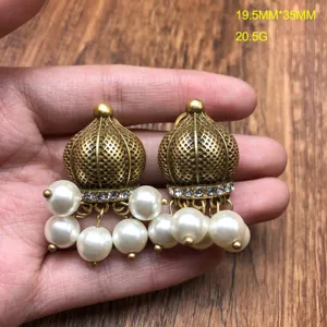 Close-up detail of vintage gold-tone dome pearl jhumka earrings showing intricate texture.