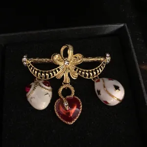 Primo piano dettaglio di spilla fiocco smalto stile vintage con pendenti unici e strass.