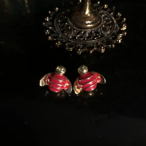 Dainty red enamel bee stud earrings with gold plating and sparkling green crystal eyes.