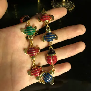 Gold plated enamel bee ladybug bracelet detail view showing colorful insect charms and delicate chain.