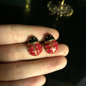 Close-up detail of cute ladybug design enamel stud earrings with gold accents and dots.