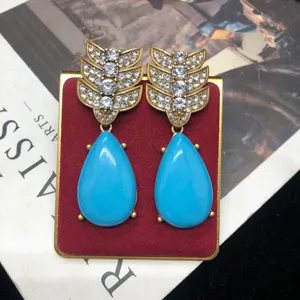 Pendientes colgantes de hoja de estrás dorados vintage y gota azul vista detallada.