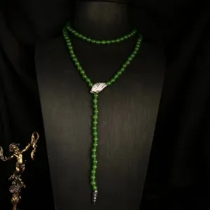 Detail view of long green beaded lariat necklace with zircon snake head pendant on black bust.