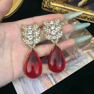Primer plano detalle de pendientes colgantes de pedrería estilo vintage retro oro antiguo.