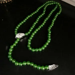 Detailed shot of vintage green beaded long necklace featuring a pave rhinestone snake head pendant.