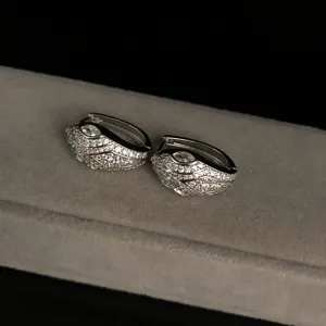 Close-up detail of silver snake hoop earrings paved with sparkling zirconia stones on velvet tray.