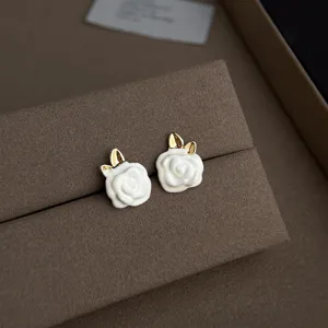 Nahaufnahme von eleganten weißen Kamelienblüten-Ohrringen mit luxuriösen goldenen Rändern.