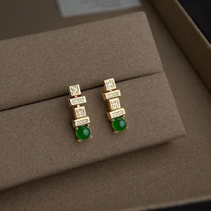 Exquisite geometrische vergoldete Zirkonia grüne Jade Ohrringe detaillierte Nahaufnahme.