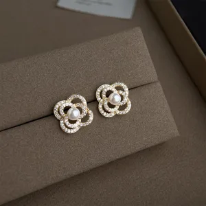 Detailansicht zarter Ohrstecker mit Zirkoniasteinen und Perle in Goldoptik, edel.