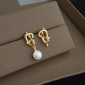 Equisite asymmetrische Perlen-Ohrringe mit einzigartigem Goldknoten-Design für Eleganz.