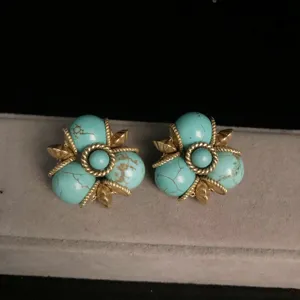 Detalle de pendientes vintage de turquesa, diseño retro dorado con motivos florales joyas.