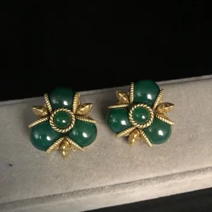 Primer plano detallado de pendientes vintage con cuentas verdes y borde dorado de estilo antiguo.