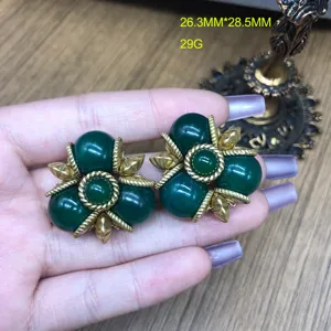Detalle de pendientes vintage de piedra verde con borde de cuerda dorada de estilo retro.
