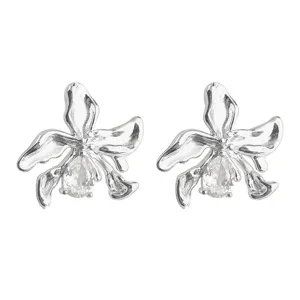 Detailed closeup of irregular liquid metal flower stud earrings featuring central cubic zirconia.