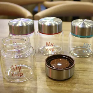 Mini glass water cup with stainless steel lid and cute letter print for portable daily use.
