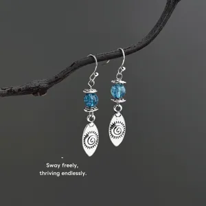 Detailed close-up of vintage silver dangle earrings with blue crystal beads and sun spiral charms.