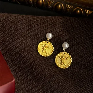 Close-up detail of vintage gold-plated angel coin earrings with elegant pearl studs.