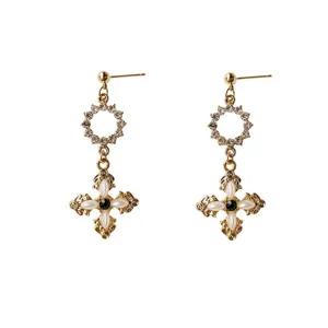 Detailed close-up of retro cross earrings featuring sparkling rhinestones and elegant pearls.
