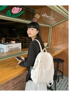 Detailed close-up view of a casual white student backpack styled in a cozy cafe interior.