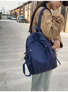 Detail view of casual nylon backpack in dark blue with multiple zipper pockets for women.
