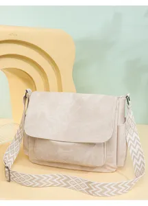 Detailed shot of a beige women's messenger bag with a wide patterned strap and flap.