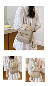 Detailed shot of beige leather mini backpack showing front zipper pocket and strap design.