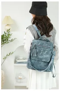 Elegante zaino da donna in pelle vintage con dettaglio nappa e tracolla larga decorata.