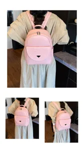 Pink leather backpack detail view showing front flap pocket and metal triangle plaque design.