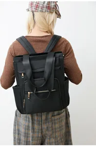 Detail view of black canvas backpack, multi-pocket design, durable shoulder and tote straps.