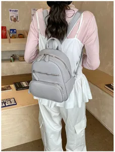 Grey leather casual backpack detail view showing the front zipper pocket and shoulder straps.