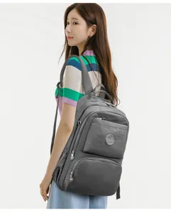 Vista dettagliata dello zaino in nylon grigio con tasche multiple con zip indossato dalla modella.