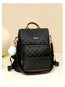 Vue détaillée du sac à dos matelassé noir avec bordure en cuir marron et pompon duveteux.