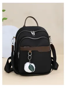 Detailed view of casual black backpack with brown leather trim and cute pom-pom leaf charm.