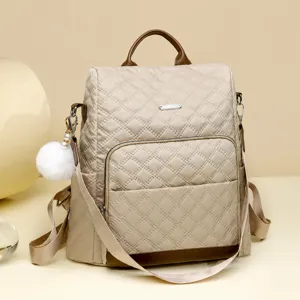 Sac à dos matelassé tendance pour femme, sac de voyage en nylon avec pompon moelleux chic.